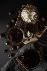 Two transparent cups of coffee, cupcake hazelnut, cinnamon sticks and retro cards on a dark grunge background. The concept. Vintage. Flat lay. Toned