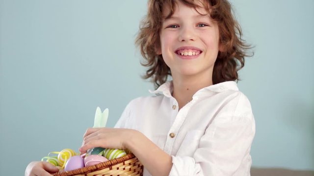 Klaus ap portrait of a curly red-haired boy with a basket of Easter eggs in his hands. Happy easter