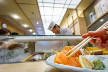Taking sushi with chopsticks in a typical Japanese restaurant