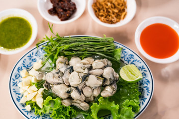 Fresh oyster, lettuce, garlic, lemongrass on a dish with various sauces