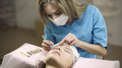Obraz na płótnie Canvas Eyelash extension in the beauty salon. The master increases eyelashes.