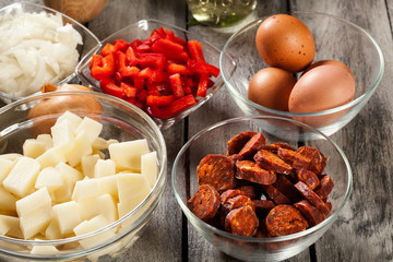 Tortilla de patatas. Ingredients for preparing spanish omelette with sausage chorizo, potatoes, paprika and egg