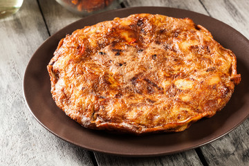 Tortilla de patatas. Spanish omelette with sausage chorizo, potatoes, paprika and egg, accompanied by olive oil