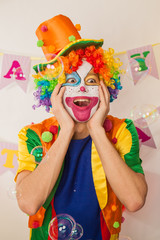 A clown boy in a bright suit at the baby's birthday party. The explosion of emotions and the fun of the circus. The sea of soap bubbles