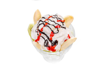 Dessert of ice cream vanilla, whipped cream, kiwi, banana, chocolate and berry topping, split, white isolated background in glass. Dish for the menu in the cafe, restaurant view from above
