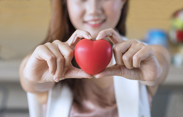 Close up, woman holding red heart in hands.