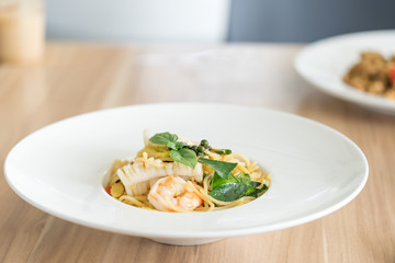 Spaghetti spicy seafood with basil on plate.