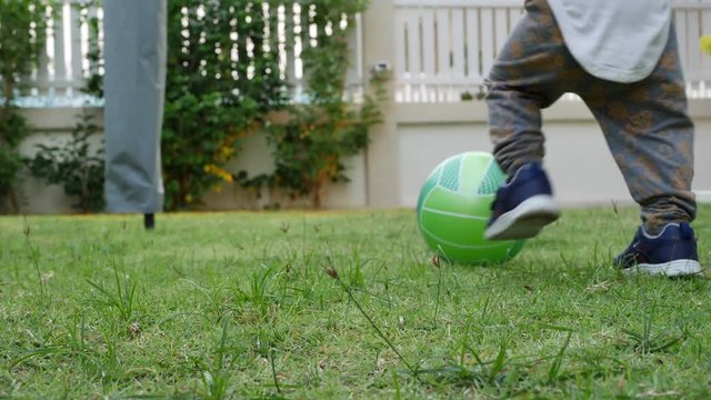 slow-motion, cute child toddle falling on green grass playing ball