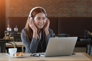 Young beautiful asian businesswoman listening music in cafe.