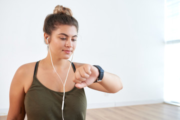 Confident sporty woman checking heart rate with help of smartwatch while having intensive training at modern health club, portrait shot