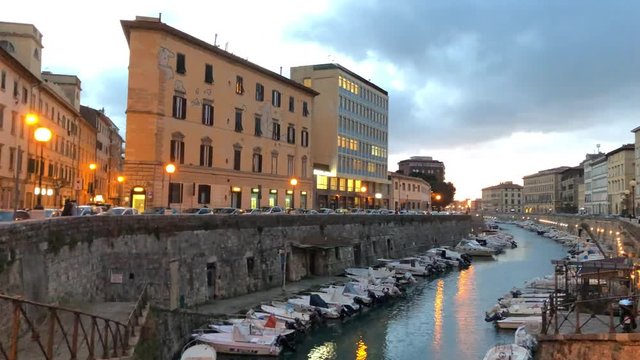 LIVORNO, ITALY - JANUARY 19, 2018: Buildings along city river with boats at sunset. The city is famous for its port