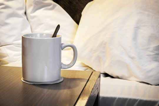 Cup Of Morning Coffee On The Bedside Table In The House Or Hotel Room. In The Background Is A Sleeper