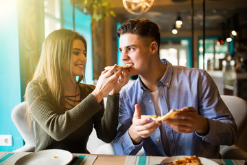 Couple sharing eating pizza snack indoors.