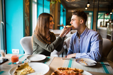 Dating in pizzeria. Handsome smiling couple sharing and enjoying in pizza, having fun together.