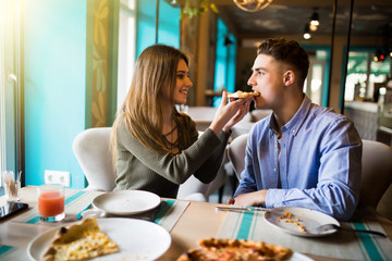 Pizza time. Beautiful loving couple sitting and eating pizza after shopping. Dating, consumerism, food, lifestyle concept
