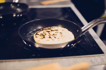 Frying traditional imeruli on frying pan in the kitchen.