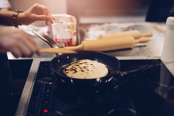 Frying traditional imeruli on frying pan in the kitchen.