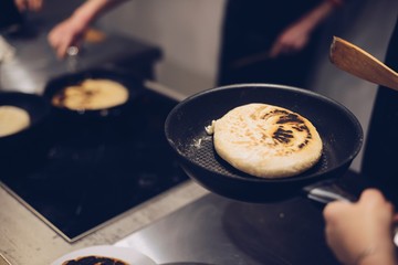 Frying traditional imeruli on frying pan in the kitchen.
