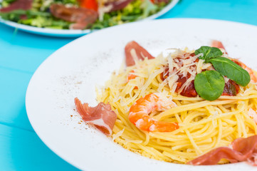 Close up of delicious spaghetti pasta in white plate on blue wooden table