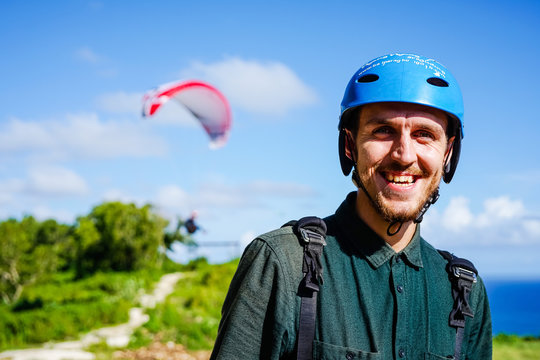 The happy face of the paraglider is close up. Paragliding over the ocean on the island of Bali. The blue sky shimmers with the blue ocean. Close-up view with copy space