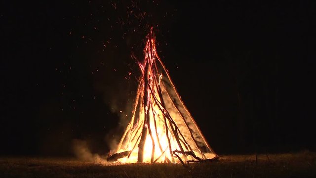 night fire sparks flying in the dark night sky, big night bonfire in a clearing in the forest