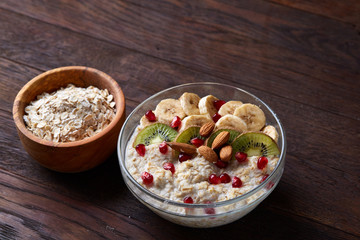 Diet breakfast oatmeal with fruits and bowl with oat flakes, selective focus, close-up