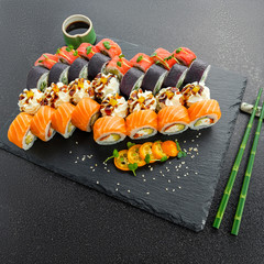 Sushi rolls, maki, nigiri Set served for two on black stone slate on dark background copy space