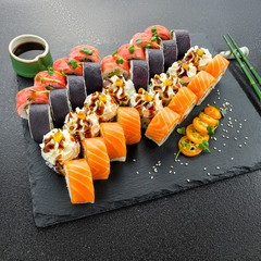 Sushi rolls, maki, nigiri Set served for two on black stone slate on dark background copy space