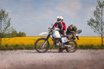 travel motorcycle off road Motorcyclist gear, A motorcycle driver looks, concept, active lifestyle, enduro, in the background a field of yellow flowers