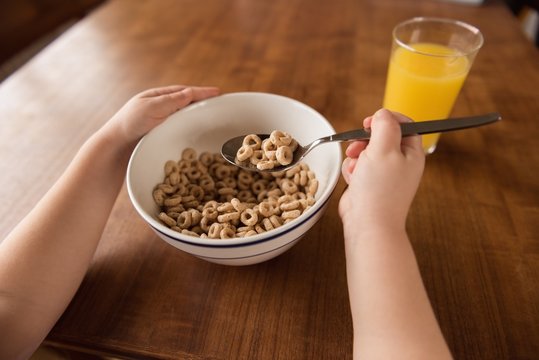 Girl having breakfast cereal and juice on table