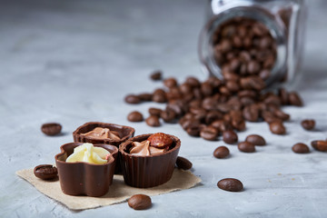 Side view of overturned glass jar with coffee beans and chocolate candies on white background, selective focus
