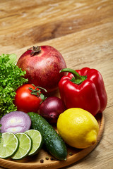 Still life of fresh organic vegetables on wooden plate over wooden background, selective focus, close-up