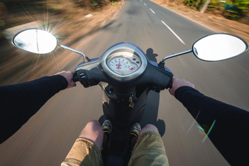 Naklejka premium Rider driving scooter on an asphalt road. Motion blurred backgro