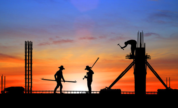 silhouette construction team working on high ground over blurred background sunset sky.