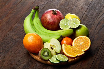 Ripe fresh fruits in a wooden plate on a rustic wooden background, selective focus, close-up, top view