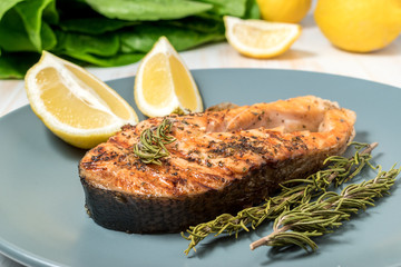 Salmon fillet. Grilled salmon with herb and lemon on plate. Fish roasted on a wooden background.