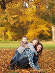 Fototapeta premium small children with mother playing in the park in autumn