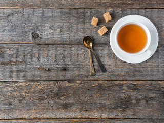 White tea Cup and saucer brown cane sugar on a rustic wooden background Copy space