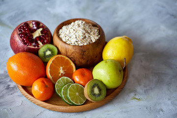 Bowl with oatmeal flakes served with fruits on wooden tray white background, flat lay, selective focus