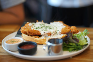 Deep fried chicken with waffle with white sauce serving tatar and tomato sauce
