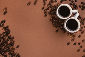 Close up top view of two cups of coffe on the brown background