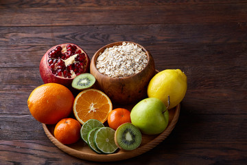 Bowl with oatmeal flakes served with fruits on wooden tray wooden background, flat lay, selective focus