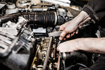 Fototapeta na wymiar Automobile service worker or garage mechanic repairing auto car engine
