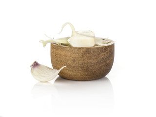 Young garlic separated cloves in a wooden bowl isolated on white background.
