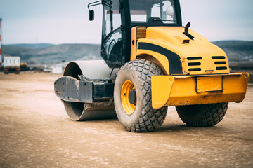 Vibratory Soil Compactor during roadworks and highway construction. Industrial construction site  with heavy-duty machinery