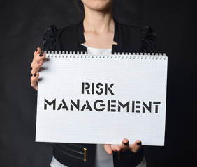 In the hands of a businessman a notebook with the inscription:RISK MANAGEMENT