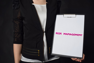 In the hands of a businessman a notebook with the inscription:RISK MANAGEMENT