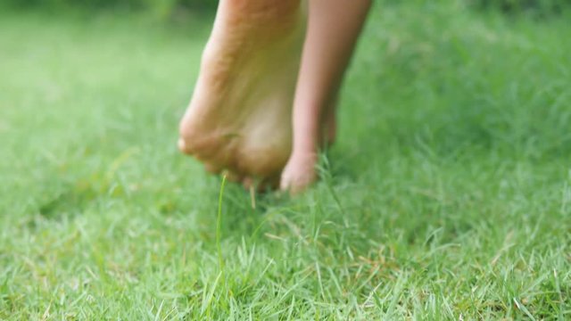 Young Woman Walking Bare Feet on Green Grass Field. 4K, Slowmotion.