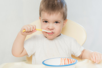 baby in the kitchen eating fruit puree