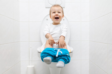 Adorable young child sitting on the toilet - obrazy, fototapety, plakaty